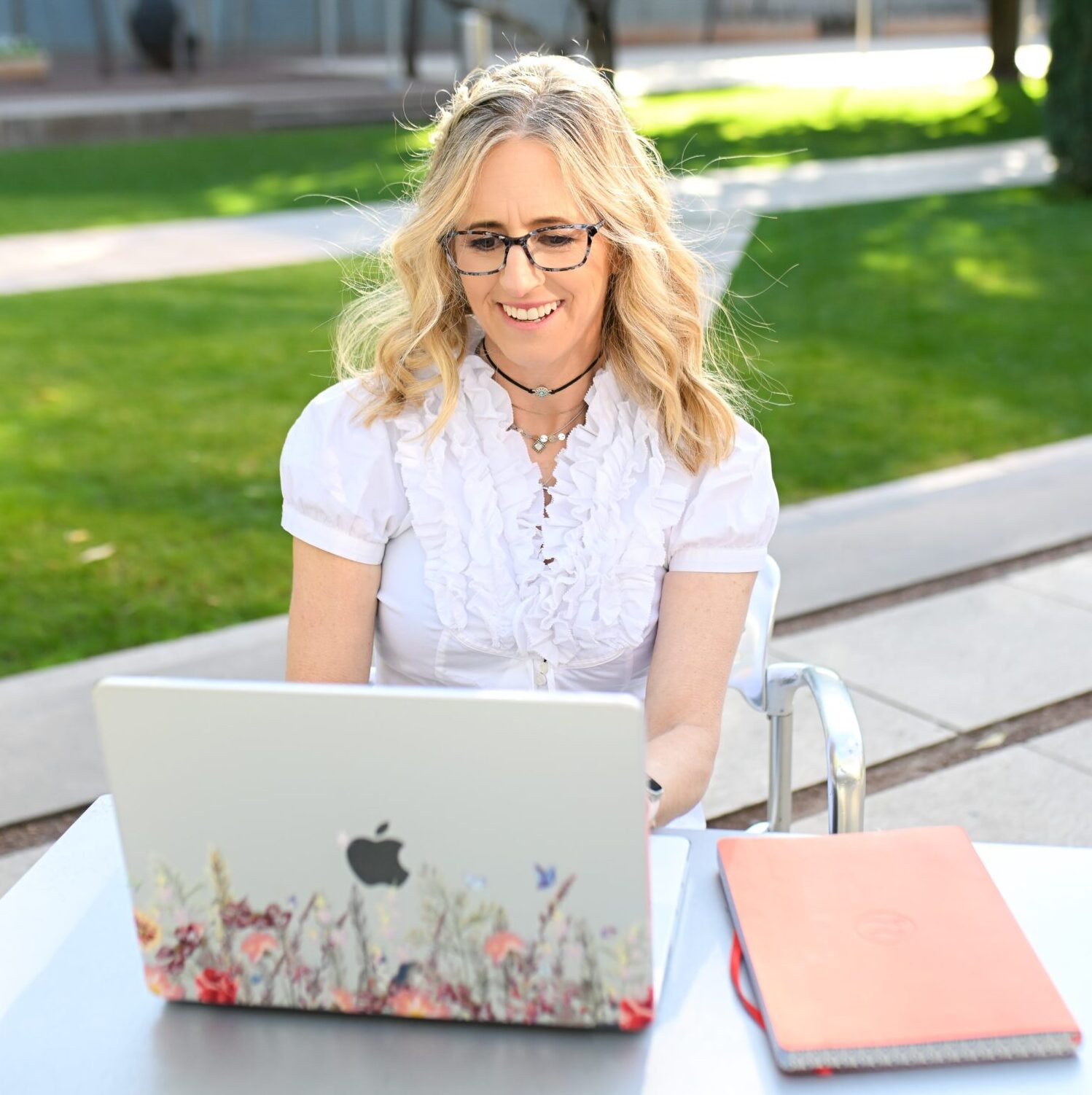 Dr. Cara Sidman, a professor of well-being, working outdoors on a laptop.